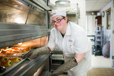 Photo of RTC student taking baked goods out of the oven.