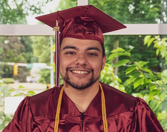 BAS grad Gianni Castellanos smiling in his cap and gown