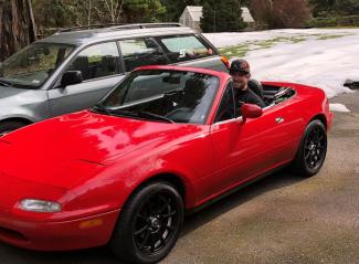 Ben Phelps sitting in his red Miata convertible car